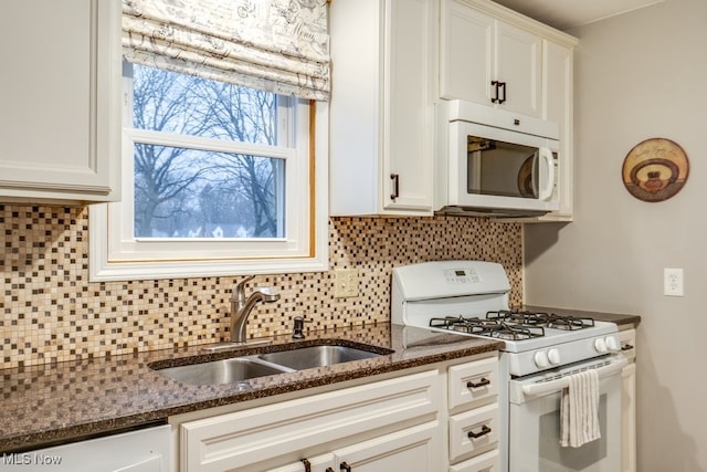 kitchen with sink, white appliances, dark stone counters, and white cabinets