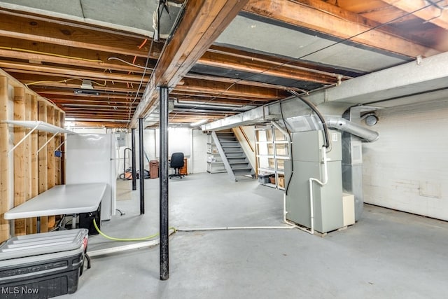 basement with heating unit and white fridge