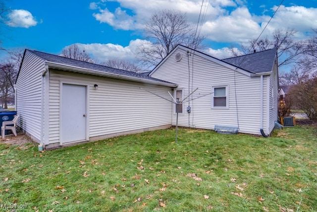 back of house featuring central AC unit and a lawn