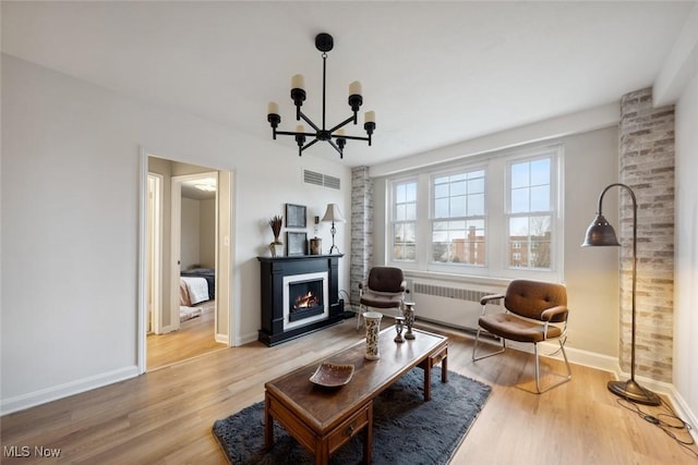 living room with an inviting chandelier, wood-type flooring, and radiator