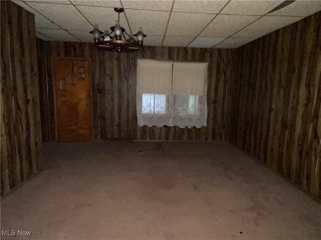 unfurnished dining area featuring a paneled ceiling and an inviting chandelier