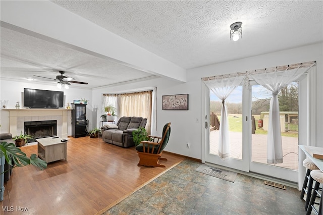 living area with visible vents, a ceiling fan, wood finished floors, a textured ceiling, and a fireplace