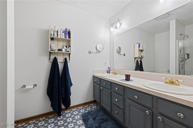 full bathroom with double vanity, a textured ceiling, baseboards, and a sink