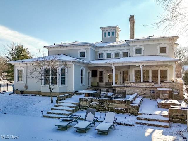 snow covered back of property featuring covered porch