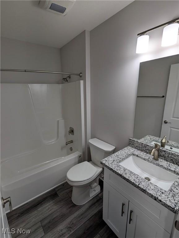 full bathroom with hardwood / wood-style flooring, vanity, bathtub / shower combination, and toilet