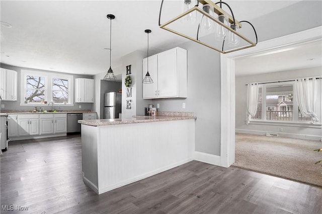 kitchen with white cabinetry, appliances with stainless steel finishes, dark hardwood / wood-style floors, and kitchen peninsula