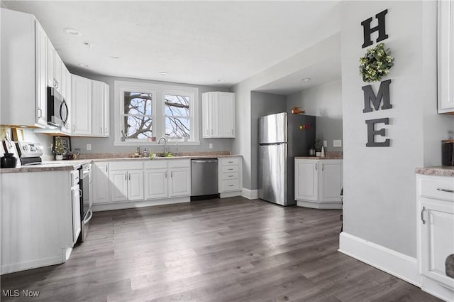 kitchen featuring stainless steel appliances, sink, dark wood-type flooring, and white cabinets