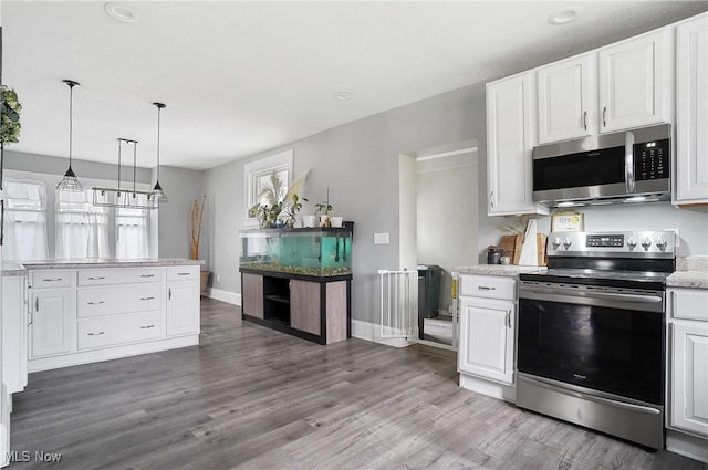 kitchen featuring hanging light fixtures, hardwood / wood-style flooring, white cabinets, and appliances with stainless steel finishes