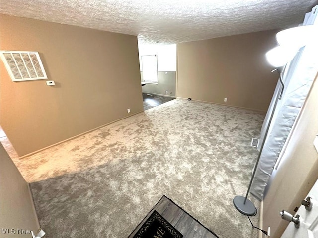 carpeted empty room with a textured ceiling