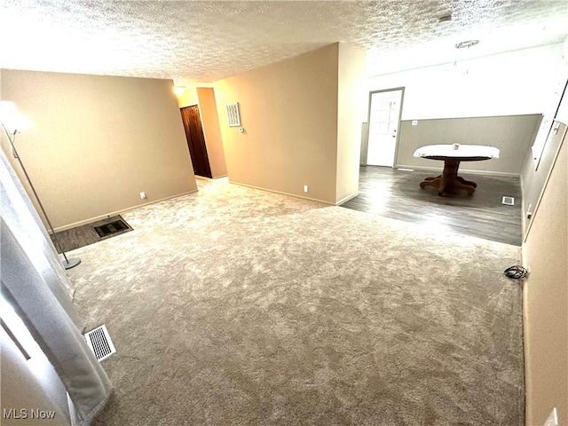 unfurnished room featuring a textured ceiling and dark colored carpet