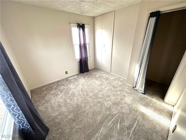 unfurnished bedroom featuring carpet floors, a textured ceiling, and a closet