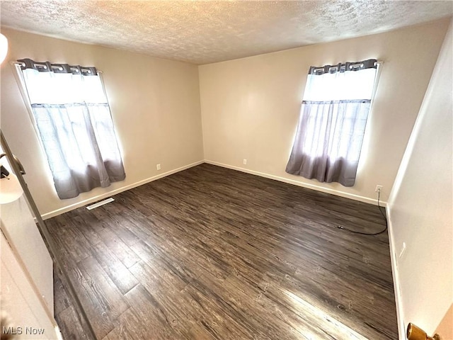 spare room with dark hardwood / wood-style floors and a textured ceiling