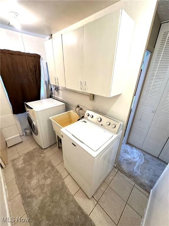 laundry area featuring cabinets, washer / dryer, sink, and light tile patterned floors