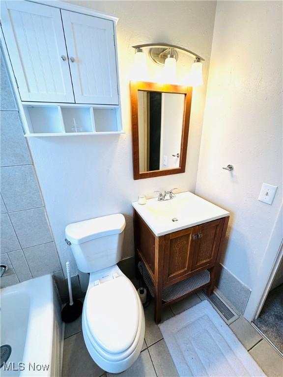 bathroom with tile patterned floors, toilet, vanity, and a tub