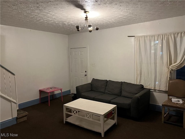 living room with an inviting chandelier, dark carpet, and a textured ceiling