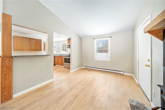 unfurnished living room featuring vaulted ceiling, a baseboard heating unit, sink, and light wood-type flooring