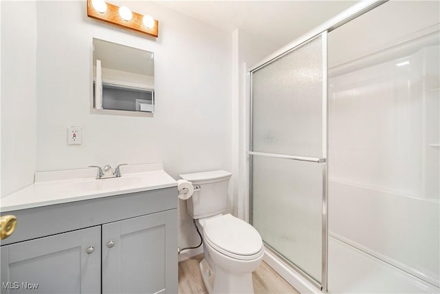 bathroom featuring vanity, hardwood / wood-style floors, an enclosed shower, and toilet