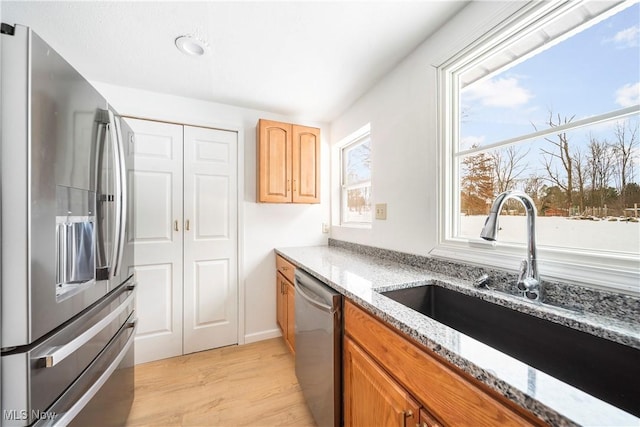 kitchen with light stone counters, sink, light hardwood / wood-style flooring, and stainless steel appliances