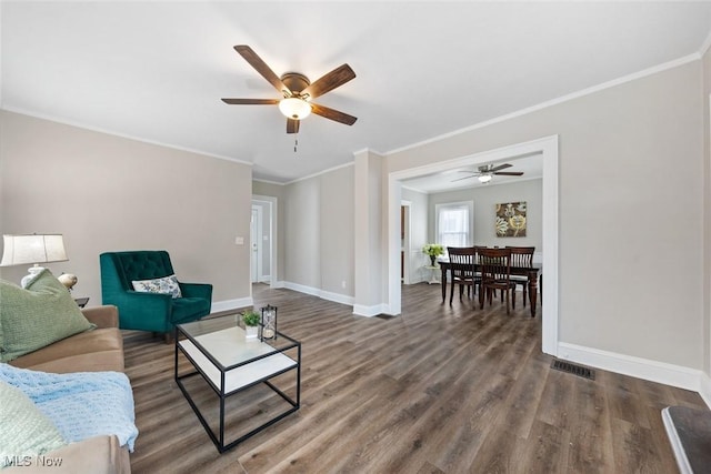 living room featuring dark wood-type flooring, ceiling fan, and ornamental molding