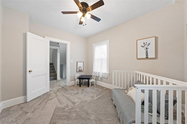 bedroom with ceiling fan, carpet, and a crib