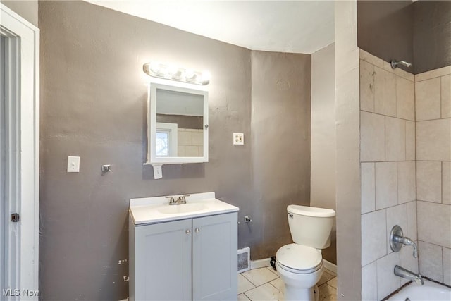 full bathroom with tile patterned flooring, tiled shower / bath, vanity, and toilet