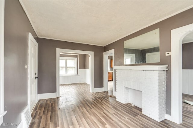 unfurnished living room with a fireplace, wood-type flooring, and ornamental molding