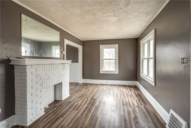 unfurnished living room with dark wood-type flooring, ornamental molding, and a textured ceiling