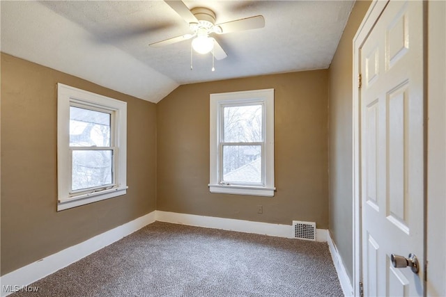 carpeted spare room featuring vaulted ceiling and ceiling fan