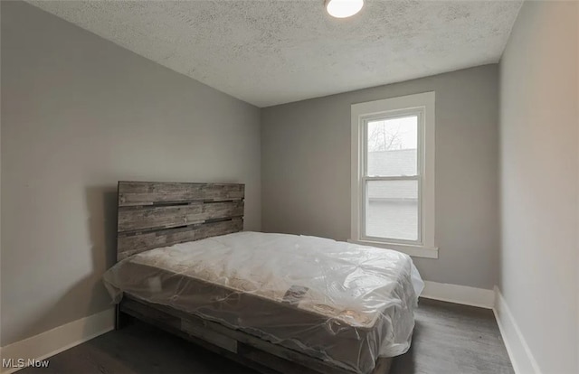 bedroom featuring dark wood-type flooring and a textured ceiling