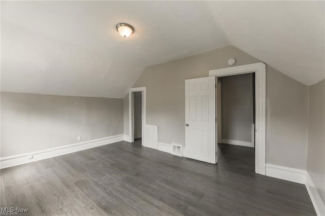 additional living space with vaulted ceiling and dark hardwood / wood-style flooring