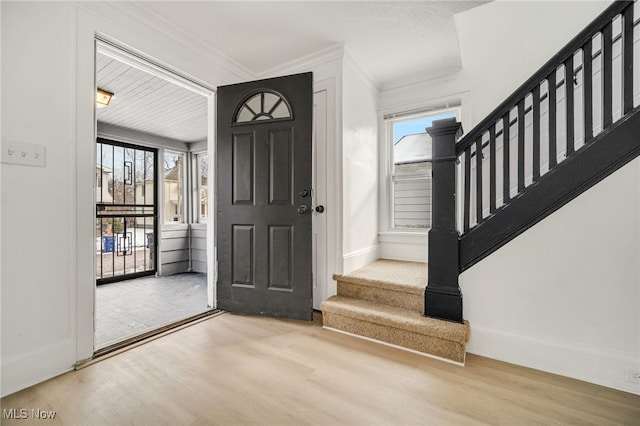 foyer entrance with crown molding, hardwood / wood-style floors, and a wealth of natural light