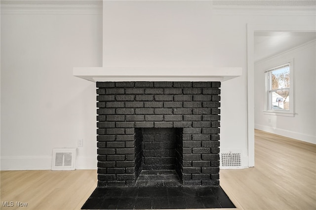 details featuring ornamental molding, wood-type flooring, and a brick fireplace