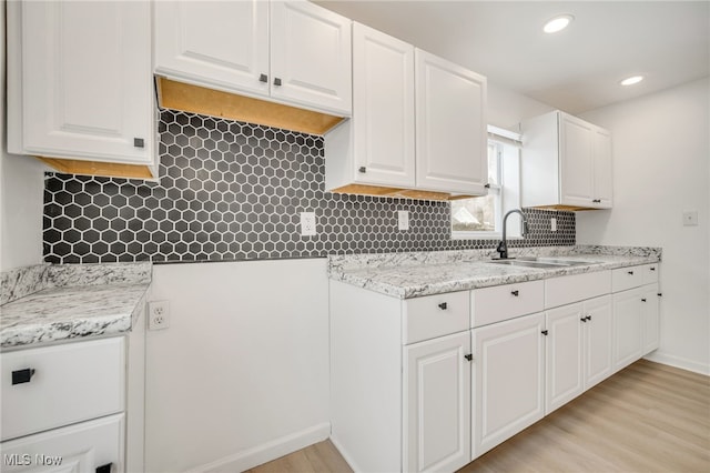 kitchen featuring white cabinetry, sink, and light wood-type flooring