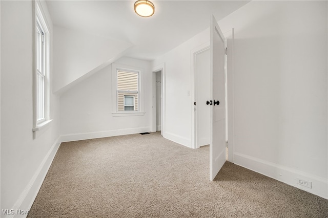 bonus room with vaulted ceiling and carpet flooring