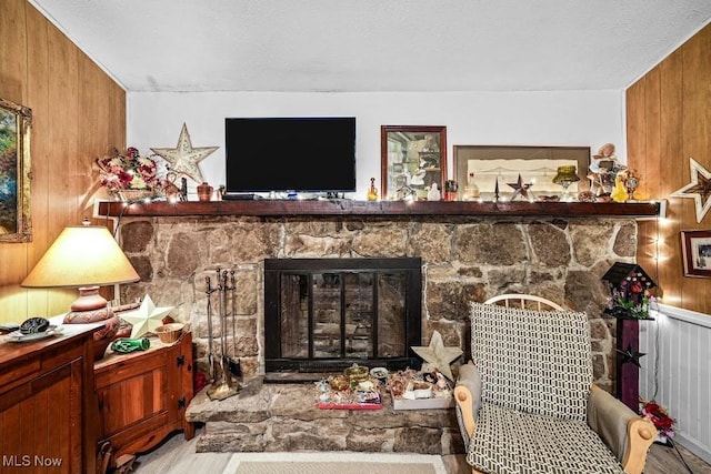 living room featuring wooden walls, a textured ceiling, and a fireplace