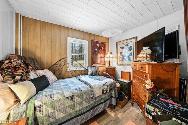 bedroom with wood walls and light hardwood / wood-style flooring