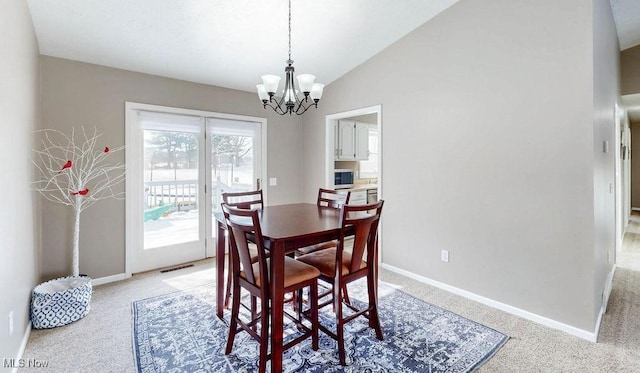 carpeted dining area with lofted ceiling and a chandelier