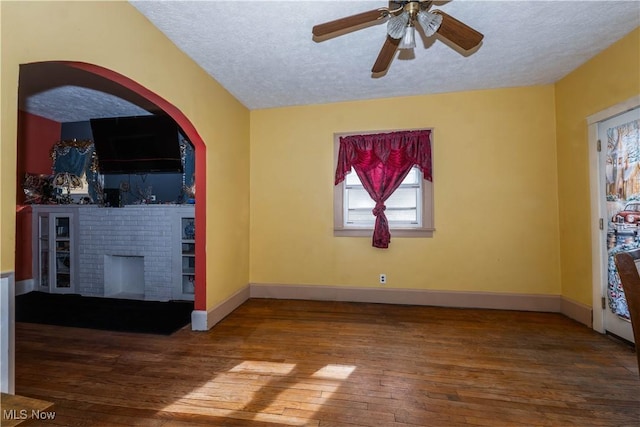 unfurnished living room featuring hardwood / wood-style flooring, ceiling fan, and a textured ceiling