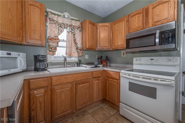 kitchen with light tile patterned flooring, appliances with stainless steel finishes, sink, and a textured ceiling