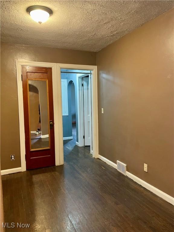 empty room featuring dark hardwood / wood-style floors and a textured ceiling