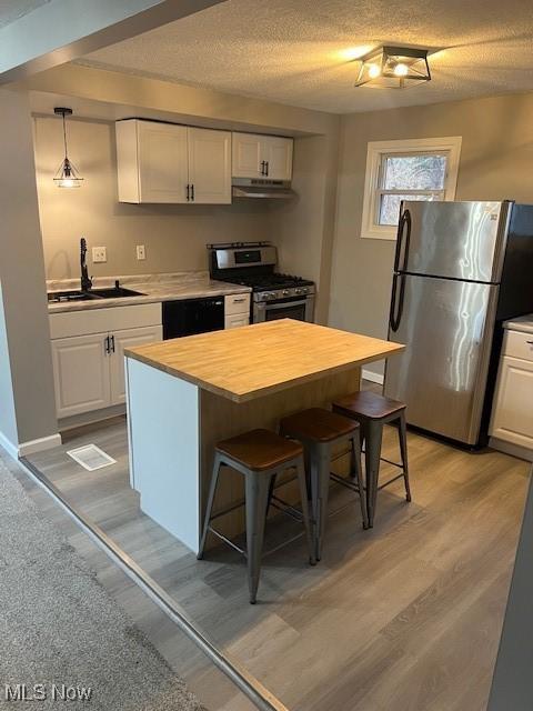 kitchen with sink, a breakfast bar area, white cabinetry, a center island, and appliances with stainless steel finishes