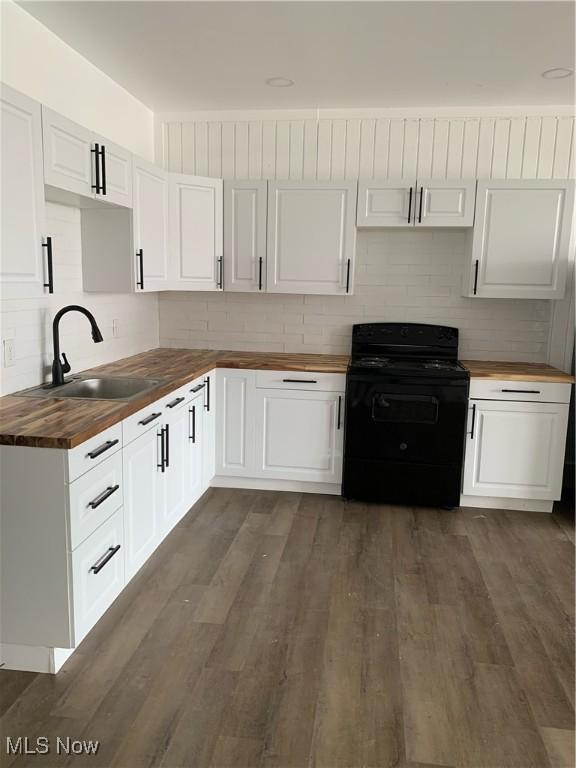 kitchen featuring white cabinetry, black electric range, dark wood-type flooring, and butcher block countertops