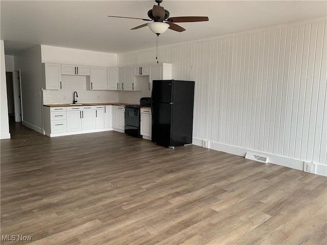 kitchen with hardwood / wood-style flooring, ceiling fan, white cabinetry, black appliances, and decorative backsplash