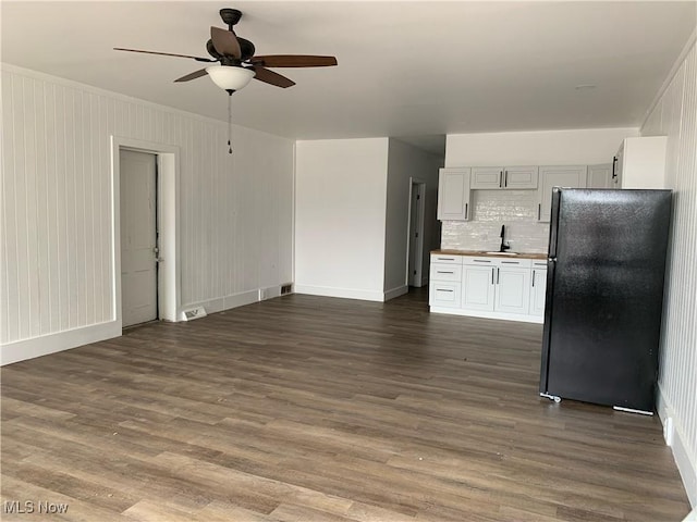 kitchen featuring black refrigerator, sink, white cabinets, dark hardwood / wood-style flooring, and decorative backsplash