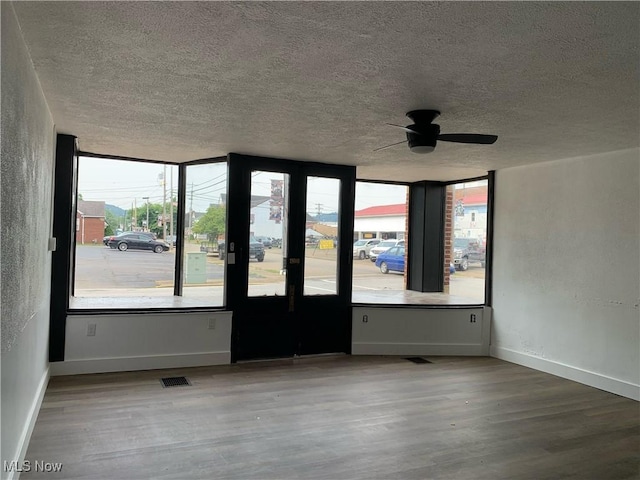 empty room with ceiling fan, hardwood / wood-style floors, and a textured ceiling