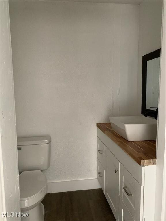 bathroom with vanity, toilet, and hardwood / wood-style floors