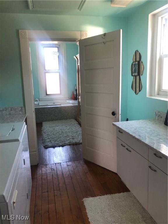 bathroom with a bathing tub, plenty of natural light, hardwood / wood-style floors, and washing machine and clothes dryer