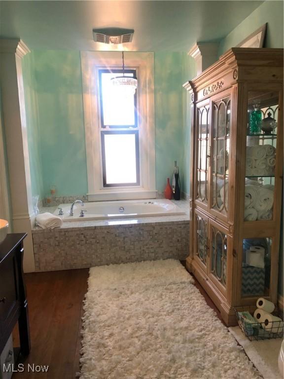 bathroom featuring vanity, tiled tub, and wood-type flooring