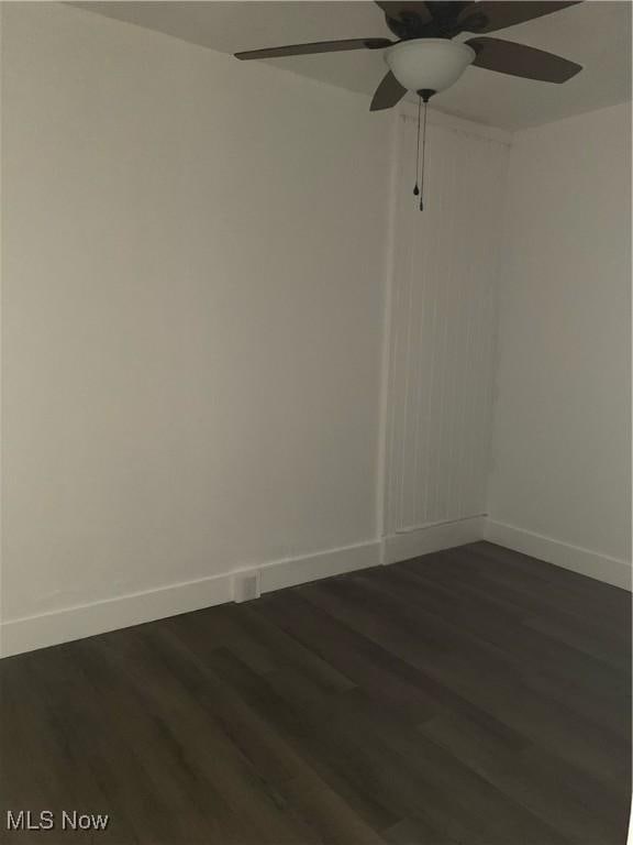 empty room with ceiling fan and dark hardwood / wood-style flooring