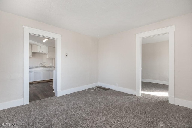 unfurnished room featuring sink and dark colored carpet